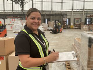 Photo of three StratAir employees holding a cargo net and smiling.